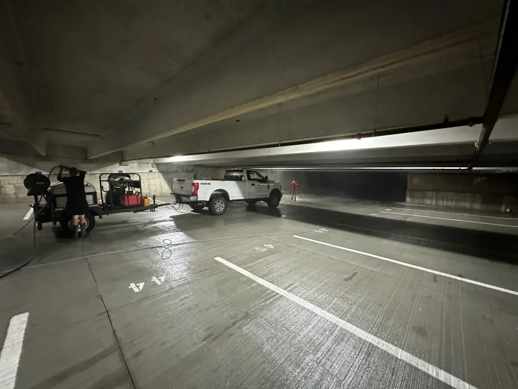 JBC crew cleaning concrete inside a parking garage
